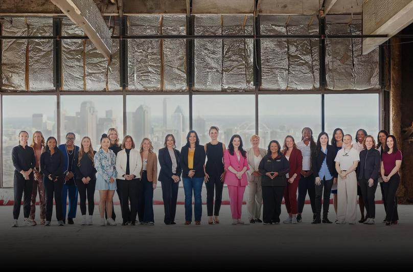 Women featured in Game Changers, standing in a row in a large room.